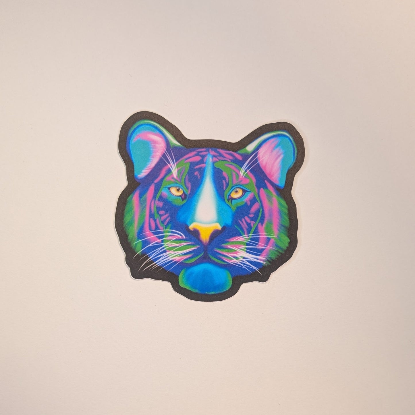 Picture of a sticker of a tiger face in neon colors on a white background.
