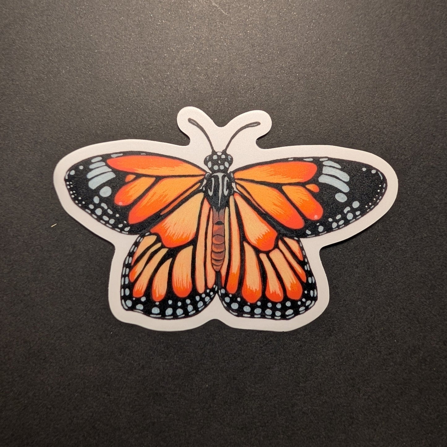 Picture of monarch butterfly sticker on black background.