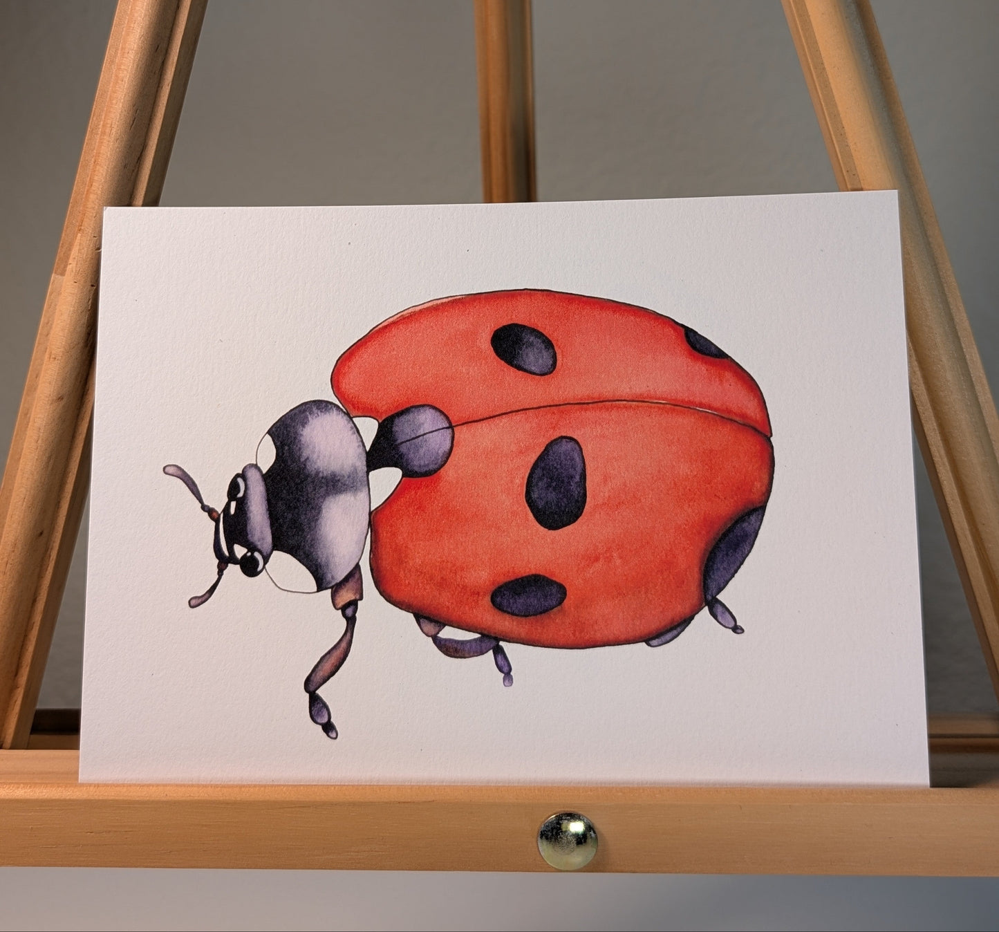 Print of a ladybug with a red shell and black spots and black head