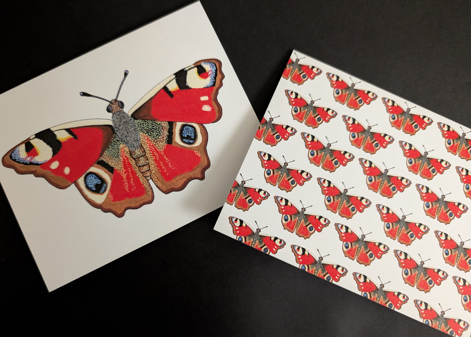 Two 4x6 cards on a black background. One card has a solo peacock butterfly on the front. The second card has a repeating pattern of peacock butterflies across the front.