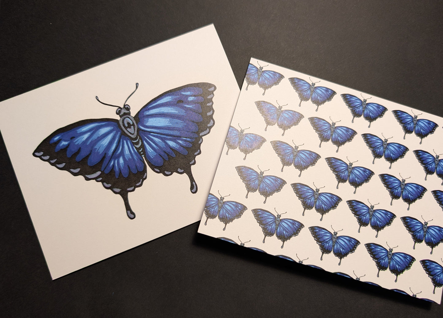 Two cards on a black background. One is a solo Ulysses butterfly on the front. The second one has a repeating pattern of Ulysses butterflies across the front.