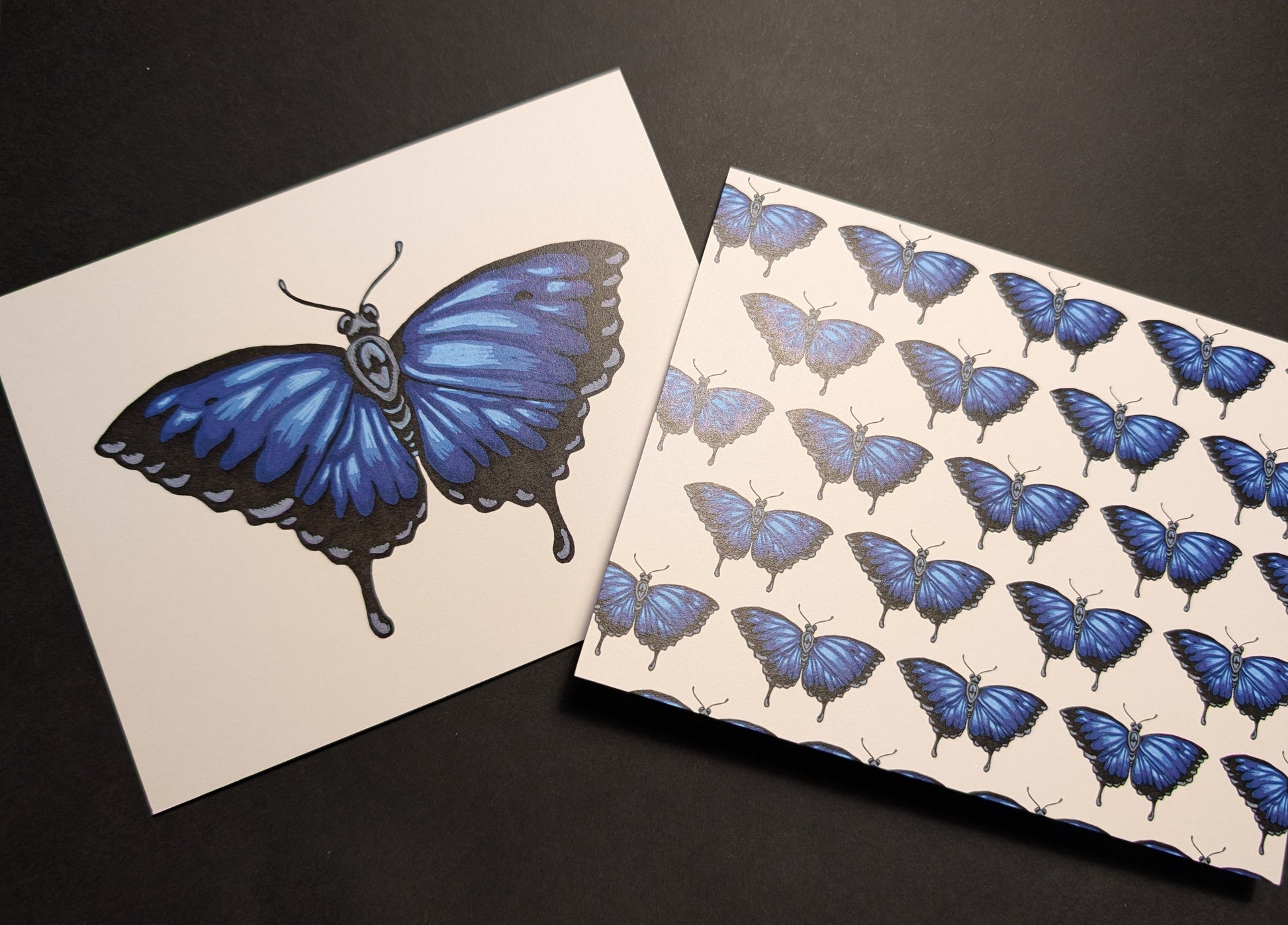 Two cards on a black background. One is a solo Ulysses butterfly on the front. The second one has a repeating pattern of Ulysses butterflies across the front.